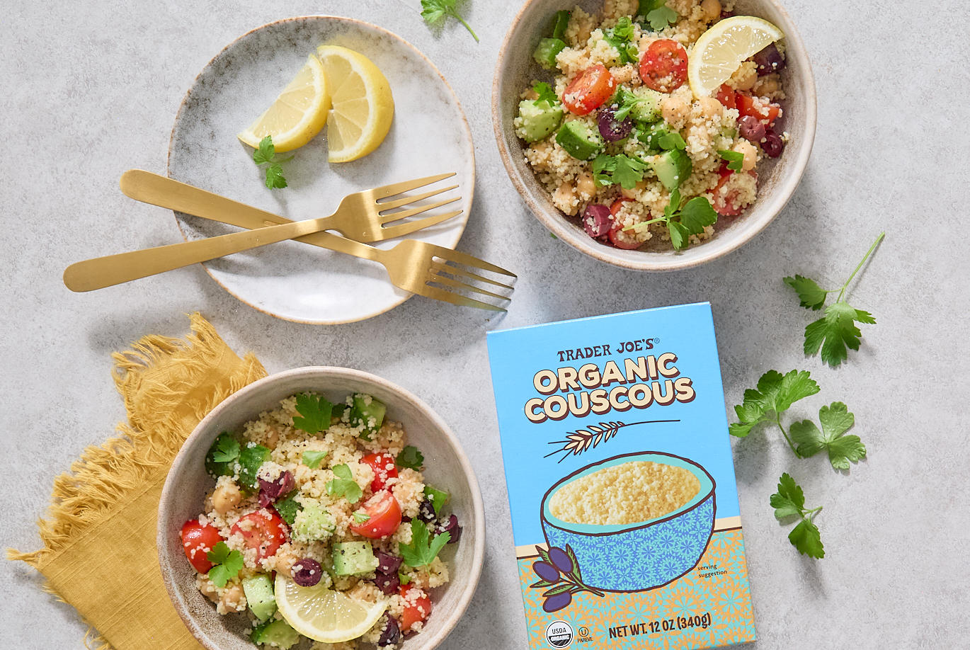 Trader Joe's Organic Couscous, in recipe for Quick Couscous Salad; in two bowls - couscous with chopped cucumber, tomato, kalamata olives parsley and lemon wedge for garnish
