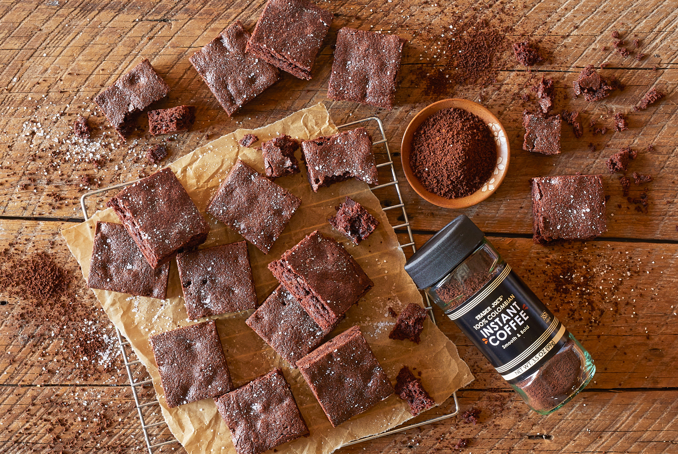Trader Joe's 100% Colombian Instant Coffee; shown used in recipe for mocha brownies; many squares of brownies on baking rack and on distressed wood surface, instant coffee sprinkled all around surface