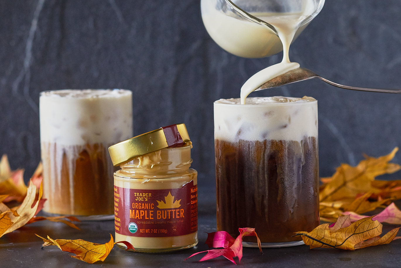 Trader Joe's Organic Maple Butter shown in recipe for Maple Cold Cream and Coffee; dark surface and background with two short glasses with cold cream and iced coffee; autumn leaves surrounding