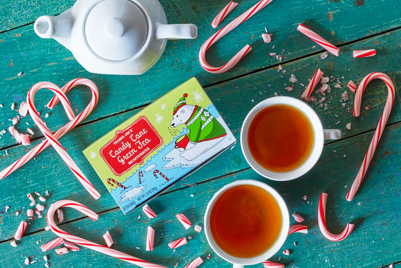 Trader Joe's Candy Cane Green Tea; on distressed wood surface, pot and two mugs of tea, candy canes and pieces surrounding